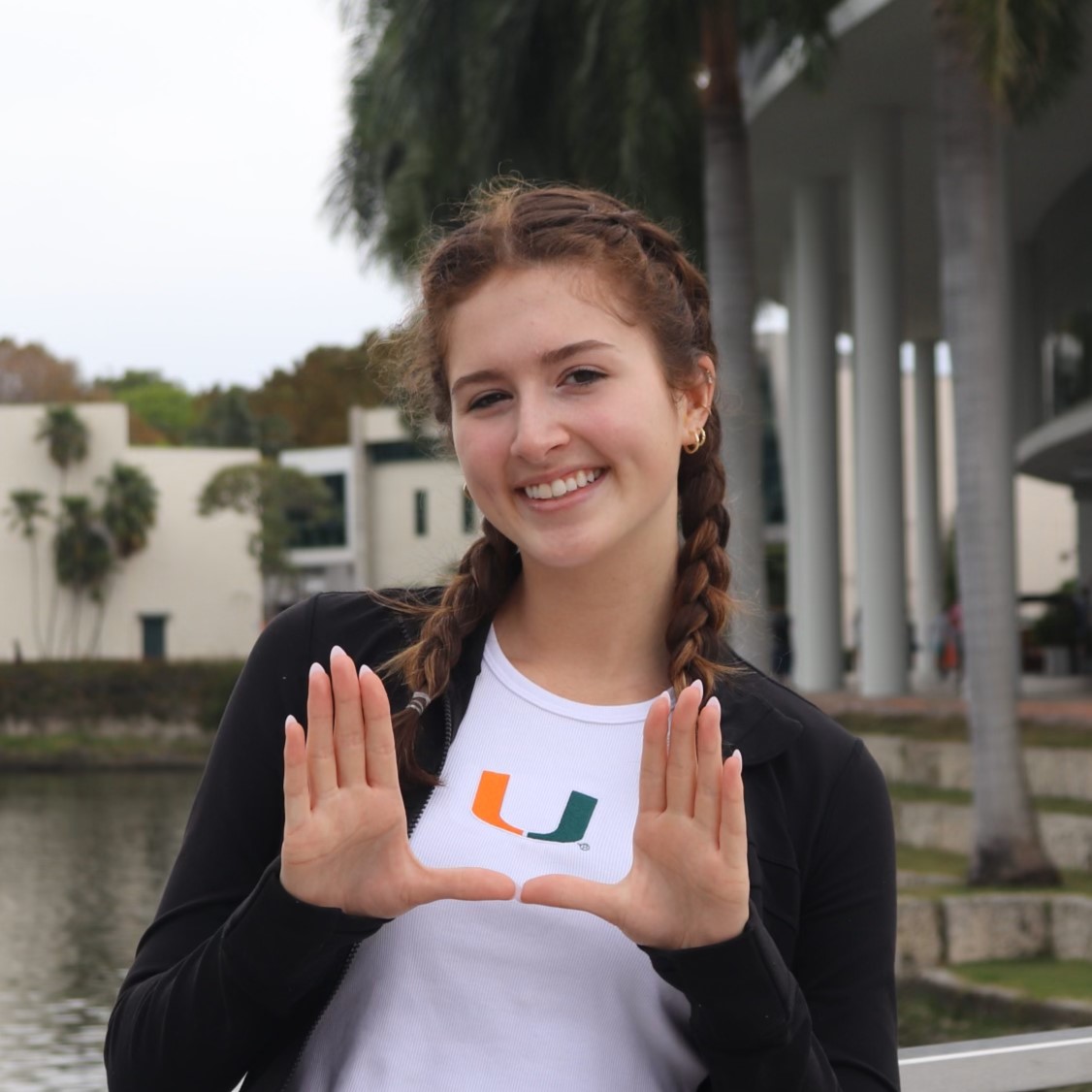 Ashley Sewall poses with hands forming a U in front of the Donna E. Shalala Student Center at the University of Miami.